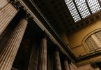 Photo of a ceiling in a courthouse with large columns and a skylight.