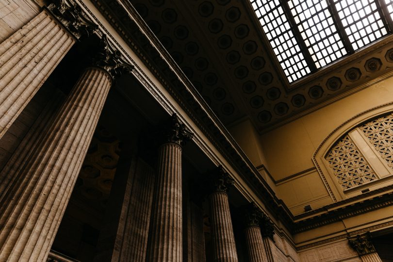 Photo of a ceiling in a courthouse with large columns and a skylight.